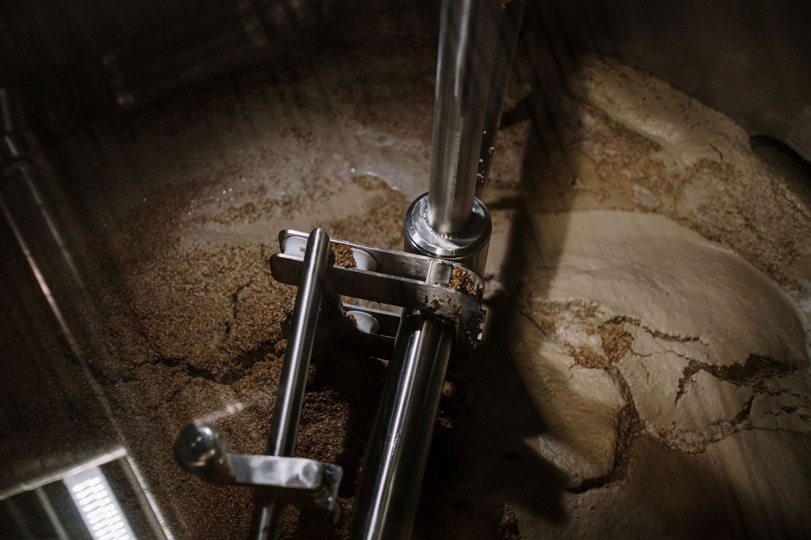 Metal mixing paddle stirring grain mash inside a brewing vessel